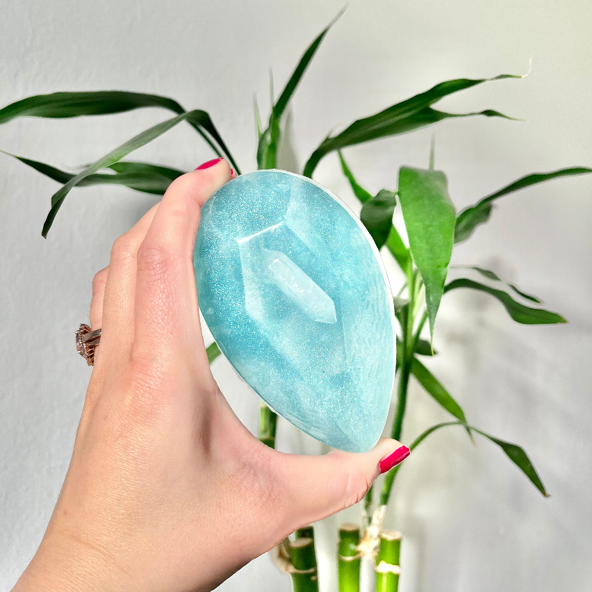 Hand holding a blue stone in front of a bamboo plant